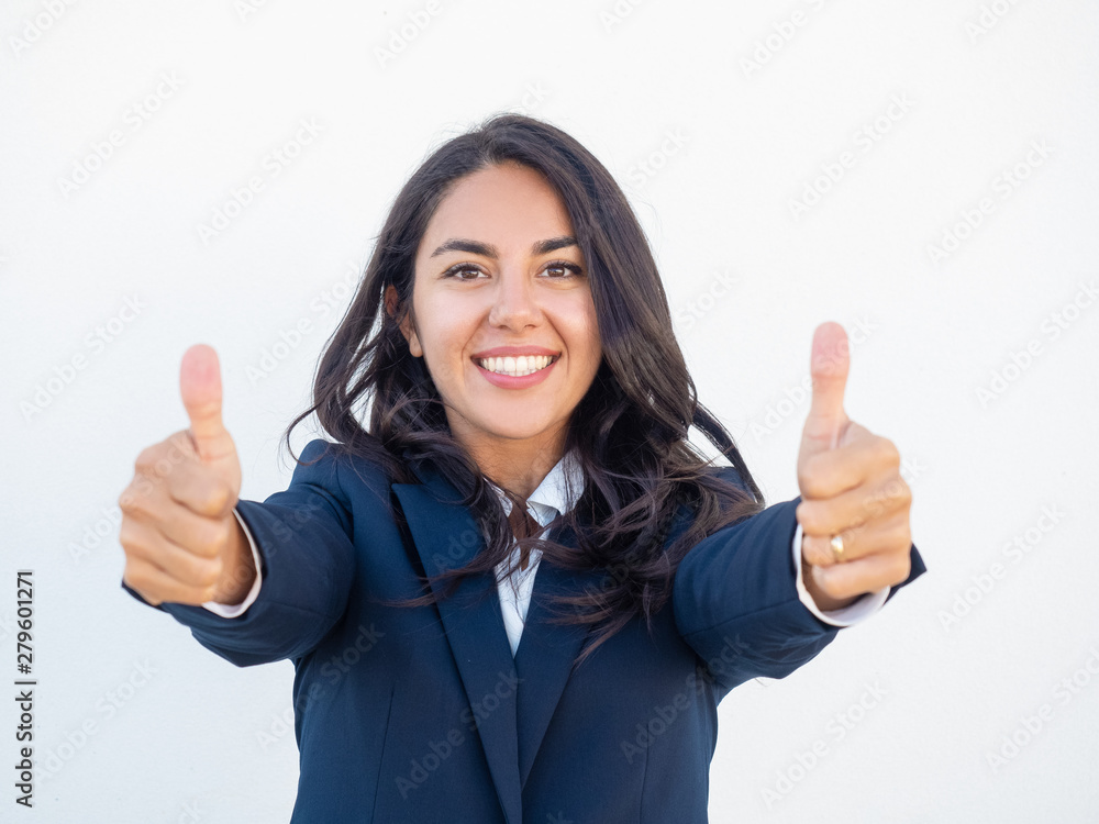 Smiling successful business leader expressing support. Happy beautiful young Latin woman in office suit showing thumbs up with both hands. Like gesture concept Smiling successful business leader expressing support. Happy beautiful young Latin woman in office suit showing thumbs up with both hands. Like gesture concept