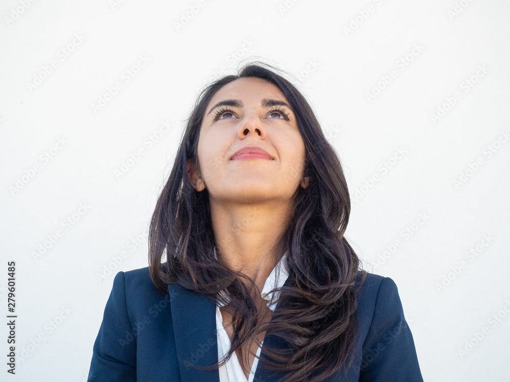 Happy young businesswoman studying information above her. Beautiful Latin woman in formal suit looking up Advertising concept Happy young businesswoman studying information above her. Beautiful Latin woman in formal suit looking up Advertising concept