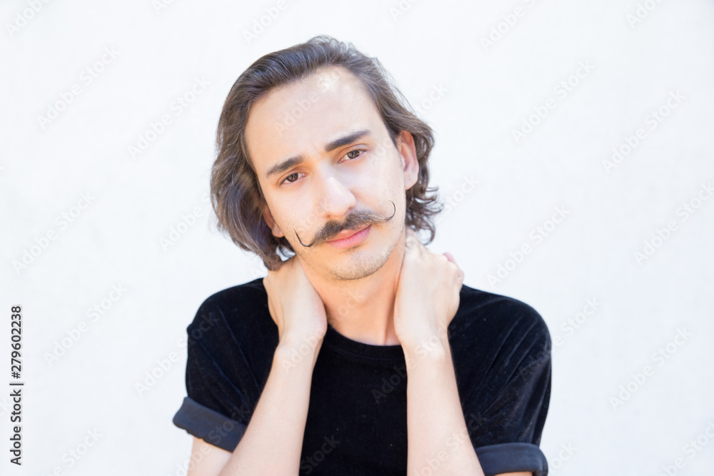 Tired young man with handlebar mustache posing. Closeup shot of confident stylish guy looking at camera and holding hands on neck. Confidence concept Tired young man with handlebar mustache posing. Closeup shot of confident stylish guy looking at camera and holding hands on neck. Confidence concept