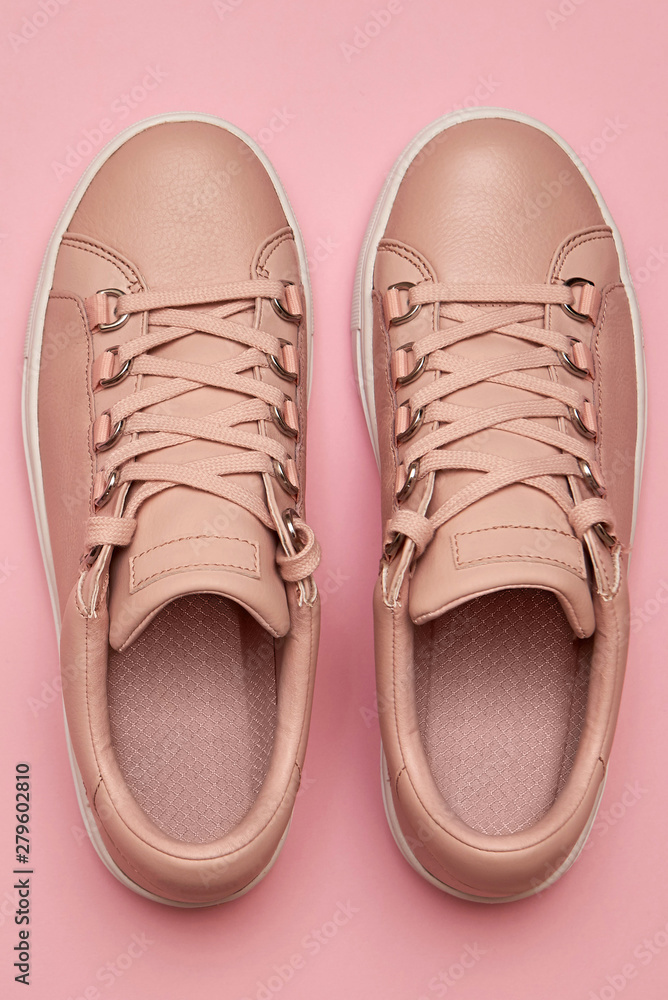 Stylish pink female shoes on pastel background, copy space. New sneakers on pink background. Beauty and fashion concept. Flat lay, top view. Overhead shot