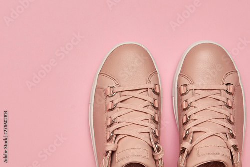 Stylish pink female shoes on pastel background, copy space. New sneakers on pink background. Beauty and fashion concept. Flat lay, top view. Overhead shot