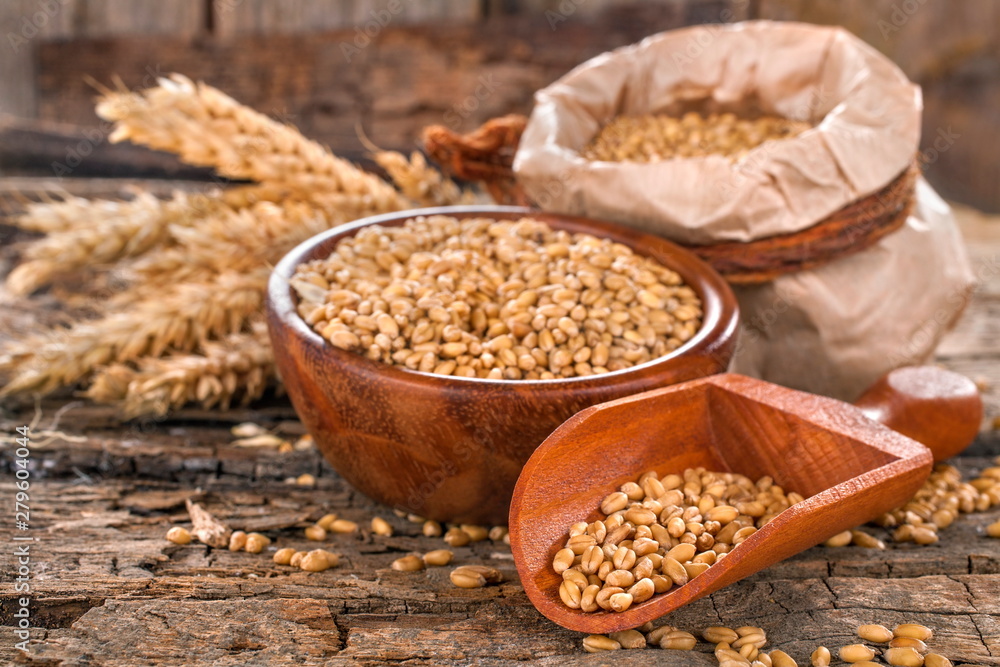 Wheat in a bag, bowl and wooden scoop on an old, rustic wooden surface Wheat in a bag, bowl and wooden scoop on an old, rustic wooden surface
