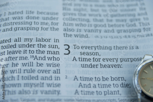 Close-up of open Bible in Ecclesiastes chapter 3 verses 1 and 2 with clock. Horizontal shot.