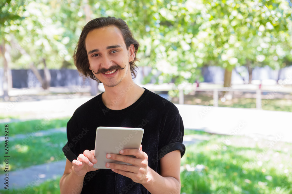 Cheerful man with digital tablet smiling at camera. Handsome man holding tablet computer and looking at camera outdoor. Digital device concept Cheerful man with digital tablet smiling at camera. Handsome man holding tablet computer and looking at camera outdoor. Digital device concept
