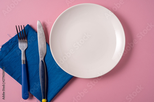 Food background with empty white plate and cutlery , over pink background, flat lay.