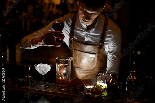 Professional bartender pouring an essence from the little glass bottle