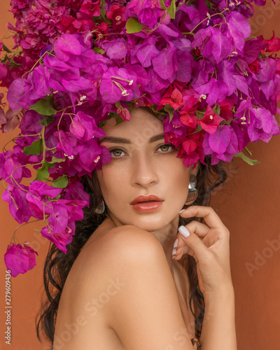 Beauty fashion model girl with pink flower on her head. Portrait on red orange background. Spa and beauty salon concept.