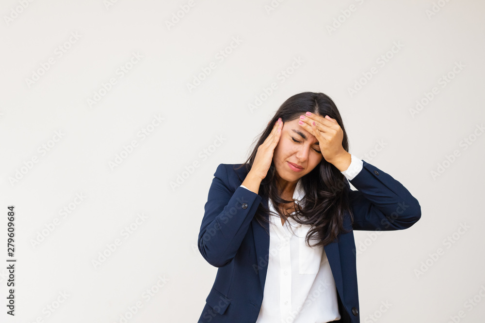 Tired young businesswoman having headache. Stressed young woman in formal wear suffering from headache isolated on grey background. Emotion concept Tired young businesswoman having headache. Stressed young woman in formal wear suffering from headache isolated on grey background. Emotion concept