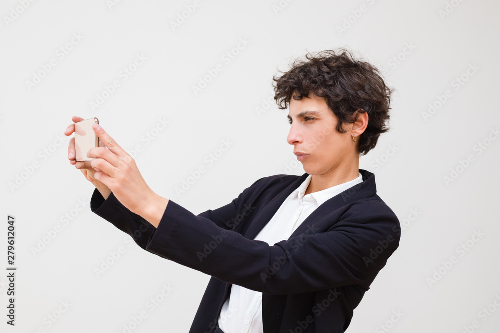 Serious businesswoman taking selfie by smartphone. Professional middle aged businesswoman using mobile phone isolated on grey background. Technology concept Serious businesswoman taking selfie by smartphone. Professional middle aged businesswoman using mobile phone isolated on grey background. Technology concept
