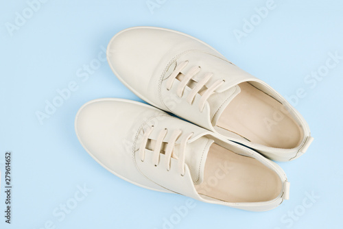 White leather casual shoes on a blue background. Copy space.