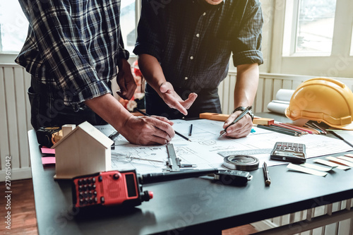 Engineer and contractor planning projects together at desk with blueprints.