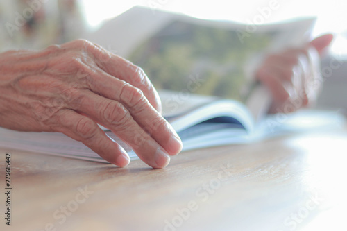 The hands of elderly people who have wrinkles are to relax and read a book in the afternoon after lunch.