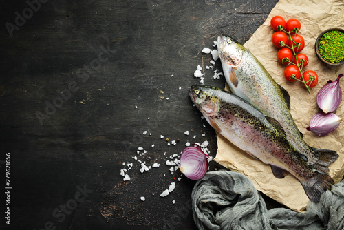 Raw fish with vegetables on a black wooden background. Fish trout. Top view. Free space for your text. photo