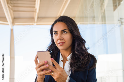 Young woman using mobile phone. Beautiful brunette woman using smartphone and looking away. Technology concept