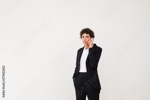 Serious businesswoman talking by cell phone. Middle aged woman in formal wear talking by smartphone and looking at camera isolated on grey background. Connection concept