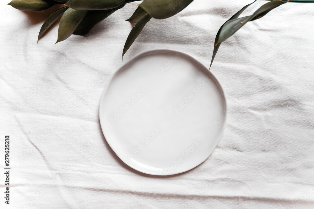 Authentic ceramic table setting mock up with linen napkin top view. Wedding holiday table setting mockup background for wallpaper, design, lettering, cards, blogs. Tableware with green branch. Authentic ceramic table setting mock up with linen napkin top view. Wedding holiday table setting mockup background for wallpaper, design, lettering, cards, blogs. Tableware with green branch.