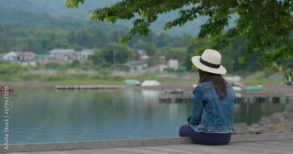 Woman sit at the lake side and look around Woman sit at the lake side and look around