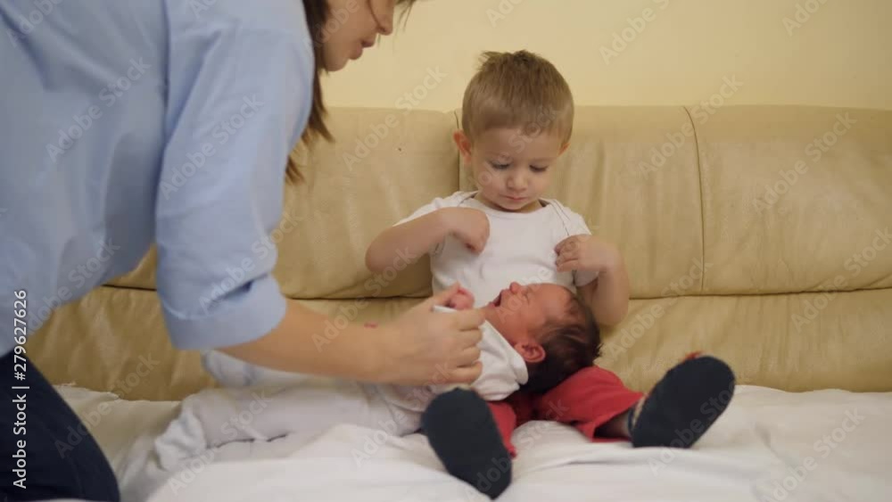 Mother giving newborn baby to little brother arms Mother giving newborn baby to little brother arms