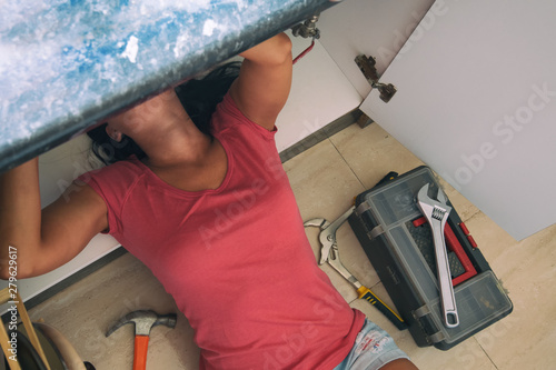 Beautiful handywoman woman fixing kitchen sink.