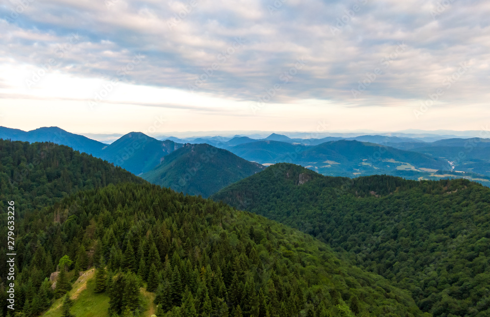 Aerial view to Mala Fatra mountains in Slovakia. Sunrise above mountain peaks and hills in far. Beautiful nature, vibrant colors. Famous tourist destination for hiking and trekking. Cloudy weather.