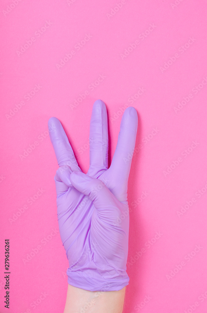 Obraz premium Human hand wearing purple, medical glove shows three fingers