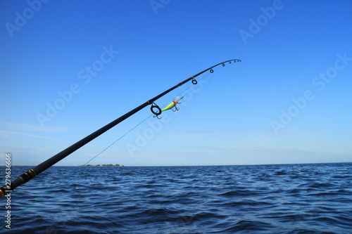 rod with crank bait for catching predatory fish aboard a boat against the blue sea and sky