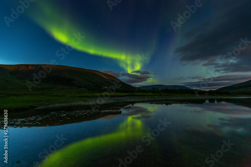 aurora borealis in the night sky cut the mountains, reflected in the water