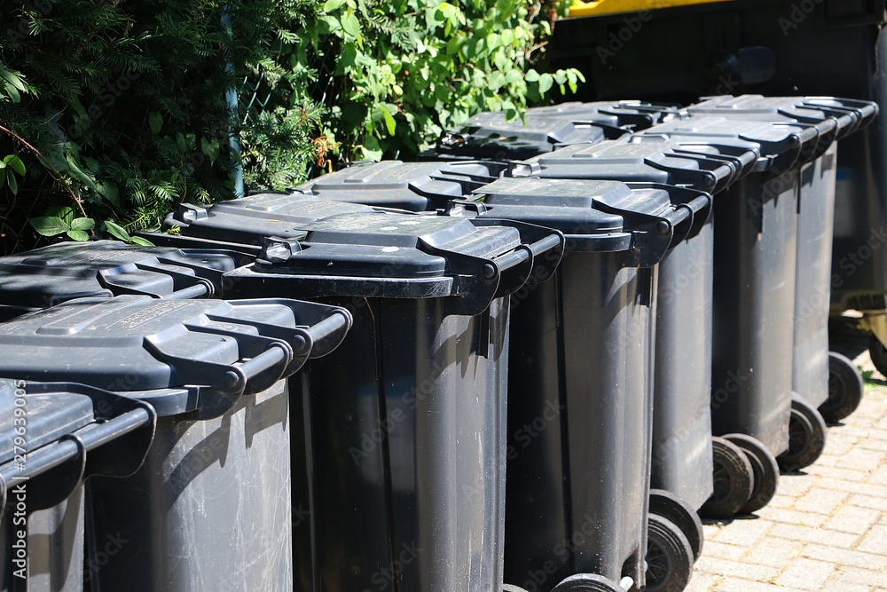 many black garbage cans are standing in a row many black garbage cans are standing in a row