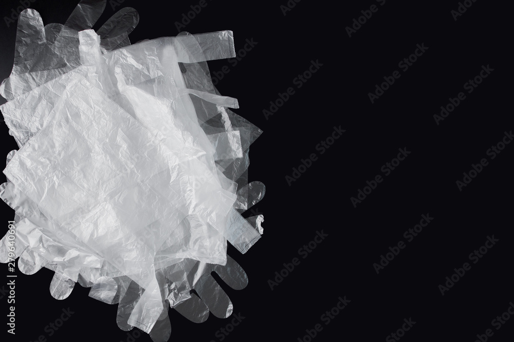 Obraz premium Plastic bag with handles, gloves, on a black background . Used plastic bag for recycling. Concept - ecology, planet pollution with plastic cellophane polyethylene