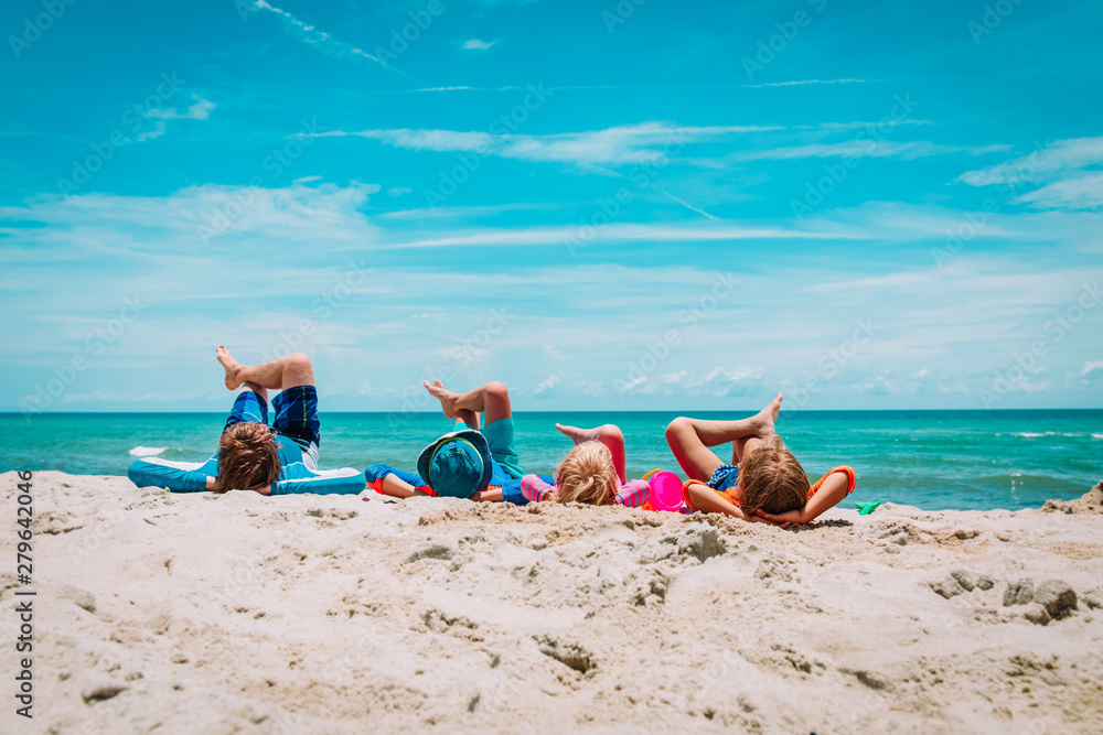 father with son and daughters relax on beach