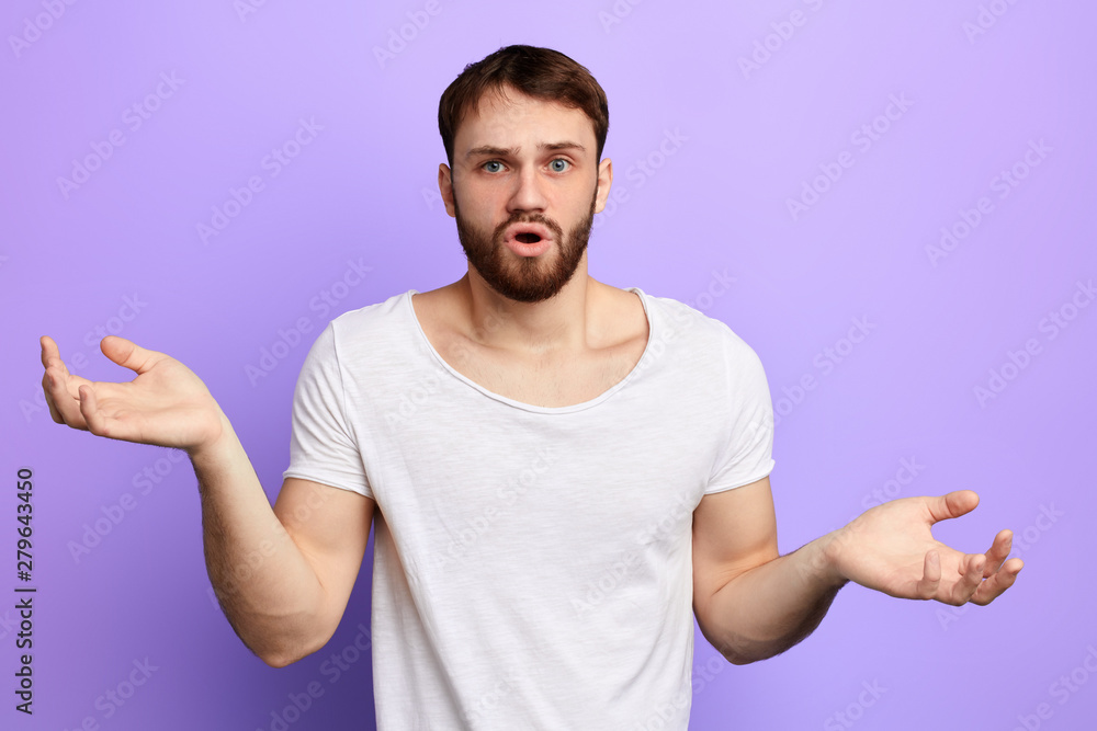 surprised handsome man shrugging his shoulder while posing to the camera. close up portrait, isolated blue background. emotion and feeling , puzzlement surprised handsome man shrugging his shoulder while posing to the camera. close up portrait, isolated blue background. emotion and feeling , puzzlement