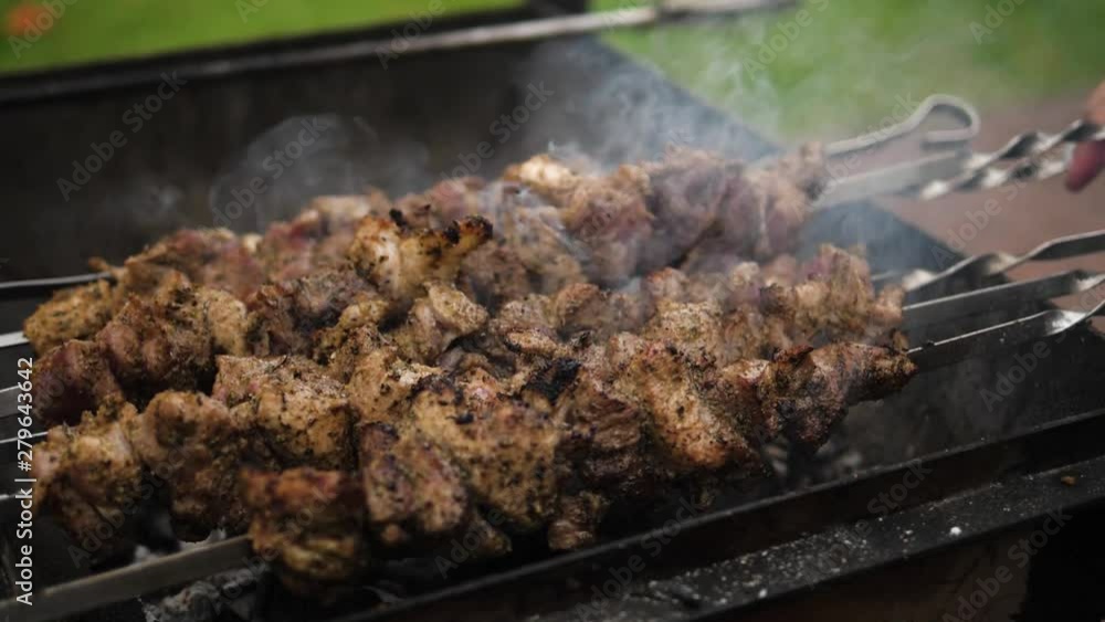 Grilling Marinated Shashlik skewered meat on a Grill BBQ. Beef prepared on fire. Barbecue party in slow motion Grilling Marinated Shashlik skewered meat on a Grill BBQ. Beef prepared on fire. Barbecue party in slow motion