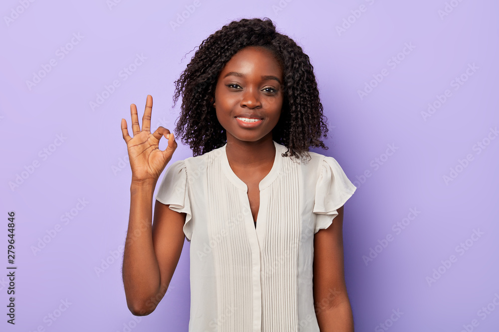 good looking american woman in white shirt smiling at camera and gesturing ok sign isolated over blue background. close up portrait, everything is ok.agreement concept good looking american woman in white shirt smiling at camera and gesturing ok sign isolated over blue background. close up portrait, everything is ok.agreement concept