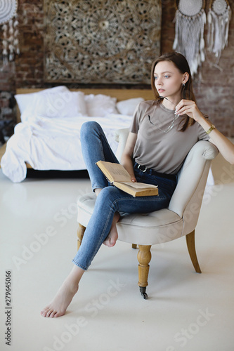 Young sweet girl with glasses sits and reads book