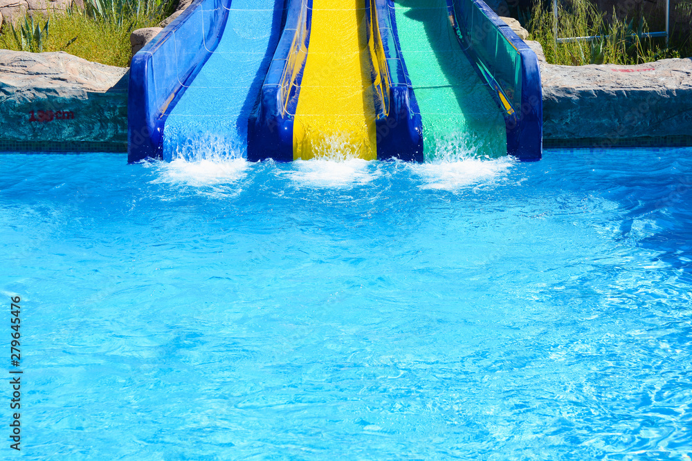 Multi-colored water slides with water jets in the blue pool