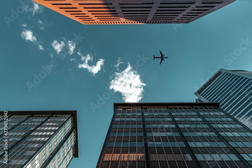 modern office apartment building with airplane flying overhead in blue sky and clouds
