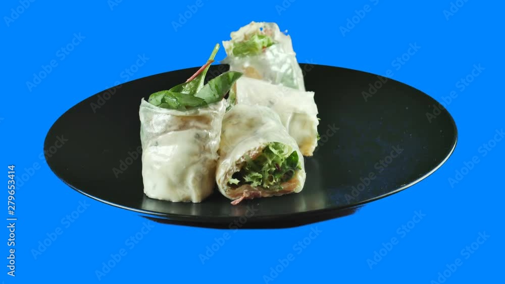 Closeup of sashimi sushi roll on a black plate rotates in a circle on an isolated blue background 50 fps 4k Closeup of sashimi sushi roll on a black plate rotates in a circle on an isolated blue background 50 fps 4k