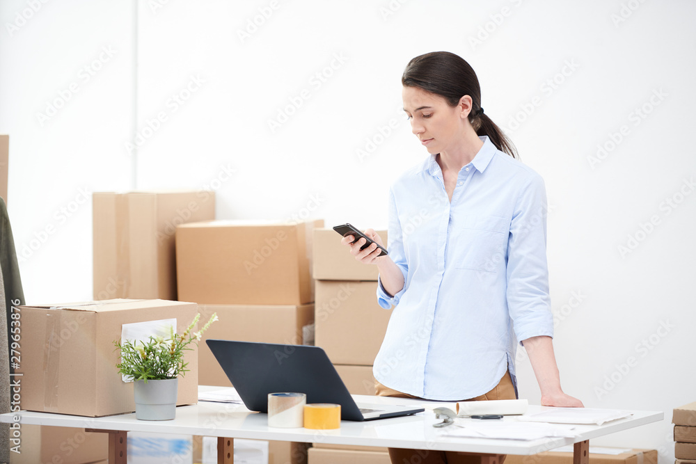 Contemporary female manager using smartphone and laptop for taking orders Contemporary female manager using smartphone and laptop for taking orders