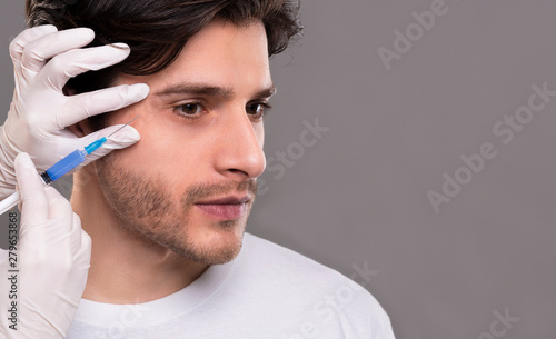 Millennial man getting hyaluronic collagen injection near eyes