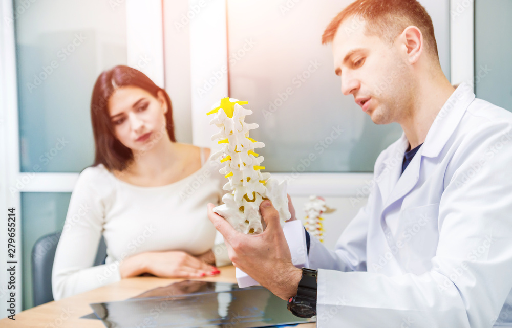 Orthopedist showing spine model to patient in hospital Orthopedist showing spine model to patient in hospital