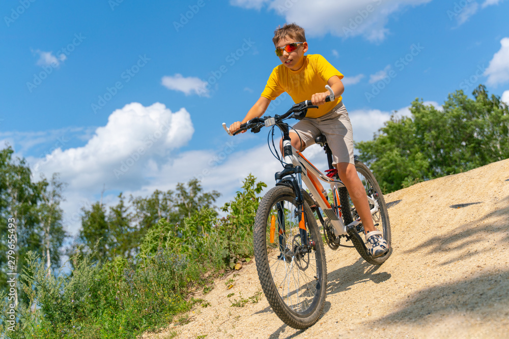 A teenager on a bike rides down a hill