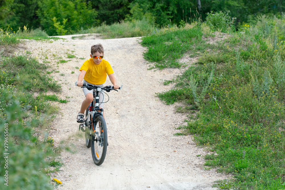 Naklejka premium A boy rides a bicycle on a hilly road cycle track