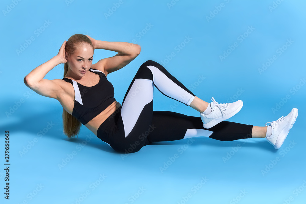 Obraz premium slim sportswoman lying on the flor and doing exercises for abs. full length photo. health and body care. lifestyle, free time, spare time