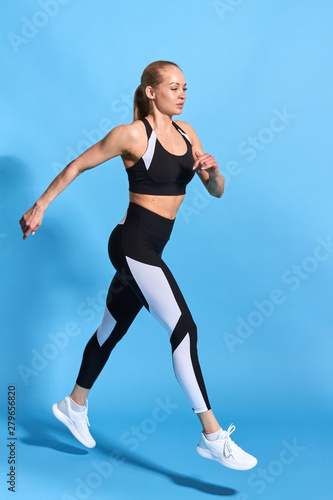 beautiful woman marching over blue background. full length photo.wellness, wellbeing, hobbby, interest . side view full length photo.