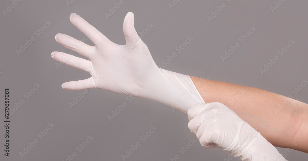 Doctor putting on sterile gloves on grey Doctor putting on sterile gloves on grey
