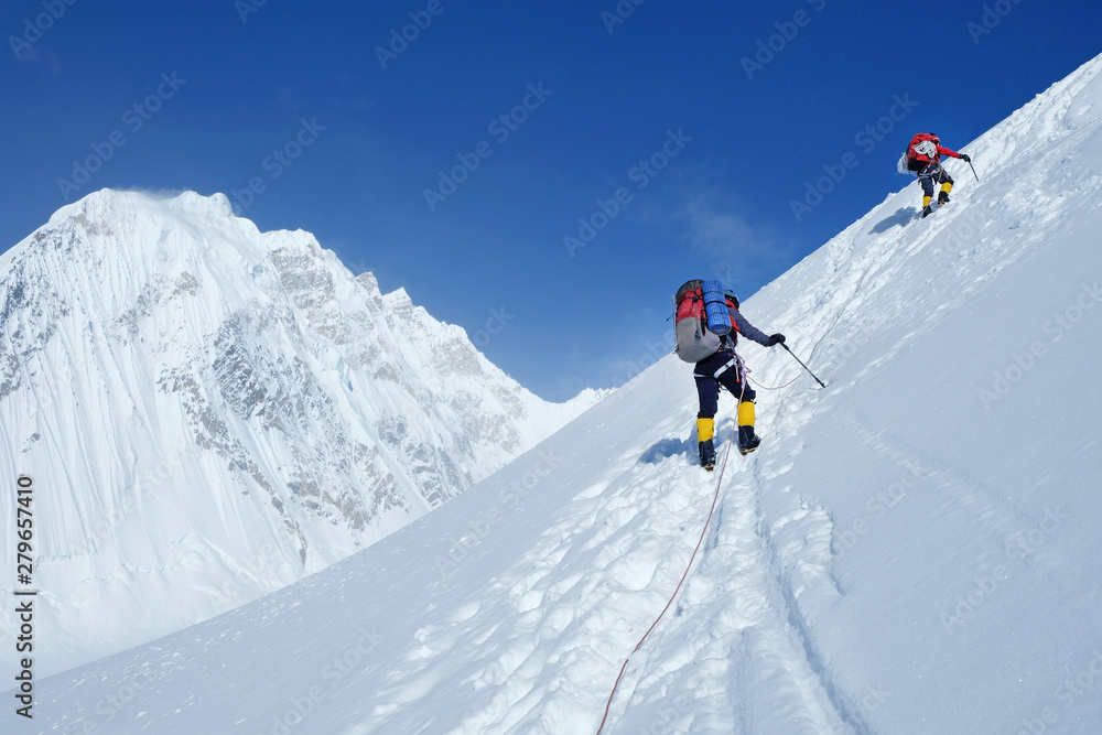 Climber reaches the summit of mountain peak enjoying the landscape view
