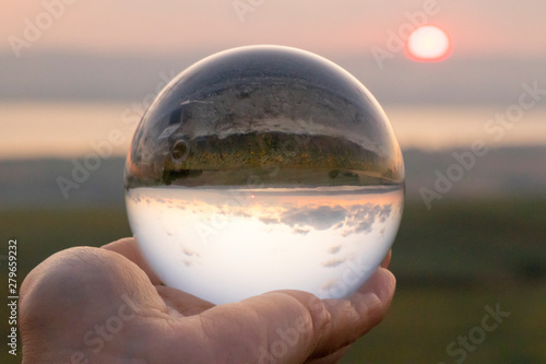 Crystal ball photography - sunset nature landscape  hand holding the ball