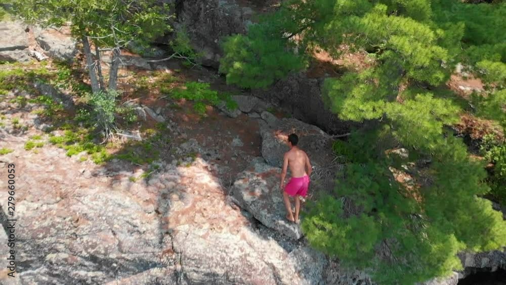 Young man doing backflip cliff jumping into lake Young man doing backflip cliff jumping into lake