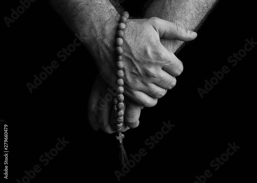 Male hands holding a church rosary. Church rosaries in the hands of men on a black background.