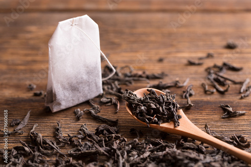 Tea bag on wooden background. Tea bag and tea leaves with a spoon on a wooden background. photo